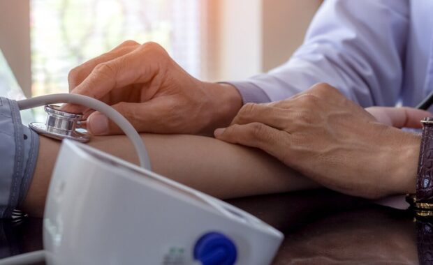 medical doctor or physician using sphygmomanometer to measure blood pressure of young female patient
