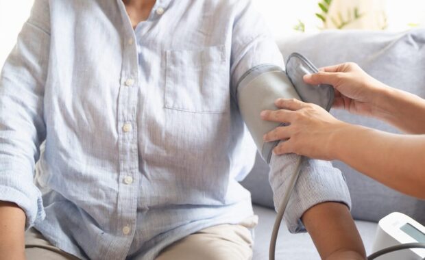 nurse measuring senior patient pulse during medical check session