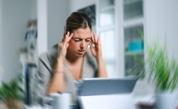 sick dizzy young woman suffering headache while working on her laptop at home