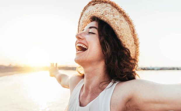 woman with arms outstretched enjoying freedom at the beach