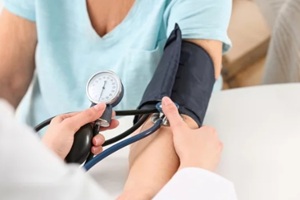 nurse measuring blood pressure of elderly woman at table