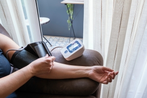 Person Measuring Blood Pressure with a Digital Monitor at Home