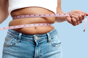 overweight woman with tape measure around waist on pastel background