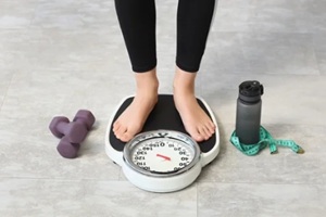 weight loss and healthy lifestyle, woman standing on bathroom scale with dumbbells and measuring tape for fitness progress and body weight management